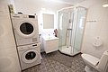 Modernes Badezimmer in Nordland, Norwegen: Waschmaschine, Trockner, geräumige Dusche, Waschbecken mit Spiegel und WC. Helle Fliesen und stilvoller Bodenbelag sorgen für ein sauberes, einladendes Ambiente. Ideal für komfortable Angelreisen-Unterkünfte.