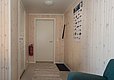 Gemütlicher Flur in einem norwegischen Angelhaus bei Hitra. Holzwände, Fischposter, Feuerlöscher, gestreifter Teppich und eine Sitzgelegenheit prägen das Ambiente. Ideal für Angelurlaub in Norwegen.