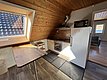 Gemütliche Ferienwohnung in Hitra, Norwegen: Dachgeschossküche mit Holzverkleidung, modernem Herd, Kühlschrank und Mikrowelle. Sonnendurchfluteter Essbereich mit Dachfenster, Blick ins Grüne. Ideal für Angelurlaub und Erholung in skandinavischer Natur.