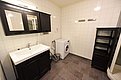 Modernes Badezimmer in Hitra, Norwegen: Waschmaschine, schwarzer Waschtisch mit Spiegel, geflieste Wände, grauer Boden. Perfekt für komfortable Angelurlaube. Entspanne nach erfolgreichen Angeltagen in dieser gut ausgestatteten Unterkunft.