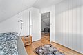 Gemütliches Skandinavisches Schlafzimmer in Nordnorwegen mit weißen Holzwänden, Holzfußboden, Bett mit blauem Muster, Nachttisch und offener Tür zum Wohnbereich. Ideal für Angelurlaub und Entspannung in natürlicher Umgebung.