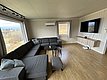 Gemütliches Wohnzimmer mit großer Eckcouch und Panoramablick, ideal für Angelurlaube in Hitra, Norwegen. Moderne Ausstattung mit Flachbild-TV und Holzfußboden, perfekt zum Entspannen nach einem erfolgreichen Angelausflug.