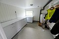 Heller Hauswirtschaftsraum in Nord-Norwegen mit drei weißen Gefriertruhen, gelber Regenjacke und Fenster. Ideal für die Lagerung frischer Fänge beim Angelurlaub. Funktionale Ausstattung für Komfort im norwegischen Angelabenteuer.