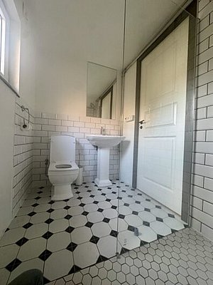 Helles Badezimmer in Nordland, Norwegen mit modernen, weißen Fliesen, Waschbecken und Toilette. Ideal für Erholung nach einem erlebnisreichen Angeltag. Komfort und skandinavisches Design vereint. Perfekt für Angelurlaube in malerischer Umgebung.