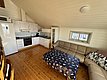 Gemütliches Apartment auf Hitra, Norwegen mit moderner Küche, komfortabler Ledercouch und maritim dekoriertem Tisch. Ideal für Angelreisen mit Wohlfühlfaktor. Helle Holzwände und Fenster sorgen für eine einladende Atmosphäre.