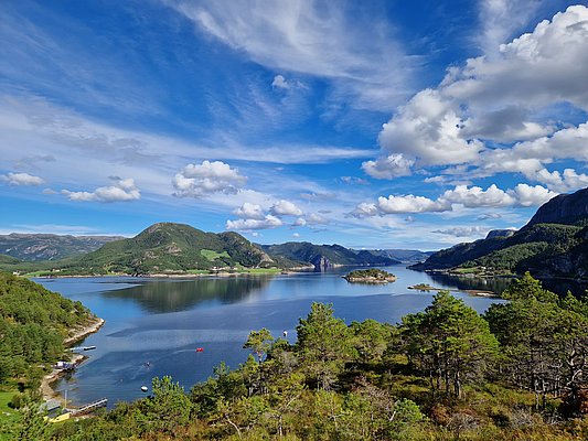 Atemberaubender Blick über die fjordreiche Landschaft von Hitra, Norwegen: Blaues Wasser, grüne Hügel und weiße Wolken bieten perfekte Bedingungen für einen erholsamen Angelurlaub in unberührter Natur. Ideal für Angelreisen und Meeresangeln.