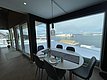 Gemütlicher Essbereich mit Panoramablick auf verschneite Küste und Meer in Hitra, Norwegen. Große Fenster schaffen eine lichtdurchflutete Atmosphäre, ideal für Angelurlaub und Entspannung. Perfekt für Naturliebhaber und Erholungssuchende.