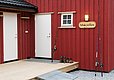 Rotes Holzhäuschen in Hitra, Norwegen, mit Angelruten, Stiefeln und Schild "Måkrellen". Perfekt für Angelurlaub. Barrierefreier Zugang zur Veranda. Ideal für Meeresangeln und entspannte Abenteuer in der Natur.
