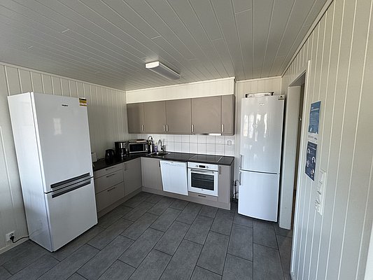 Moderne Küche in Hitra, Norwegen: helle Schränke, geräumiger Kühlschrank, Backofen, Mikrowelle und Spüle. Ideal für Angelurlauber, die Komfort schätzen. Perfekte Ausstattung für selbstgekochte Mahlzeiten nach einem erfolgreichen Angeltag.