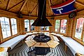 Ein gemütlicher, holzverkleideter Pavillon in Nord-Norwegen mit offenem Kamin, Sitzbänken und Blick auf die malerische Fjordlandschaft. Perfekt für einen entspannten Angelurlaub in eindrucksvoller Naturkulisse.