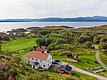 Luftaufnahme der idyllischen Küstenlandschaft von Hitra, Norwegen: Grüne Wiesen, traditionelle Häuser und weite Ausblicke aufs Meer bieten perfekte Bedingungen für einen erholsamen Angelurlaub und Naturgenuss.