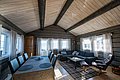 Gemütliches Wohnzimmer in einer Holzhütte in Nord-Norwegen. Die Einrichtung kombiniert moderne und rustikale Elemente mit einem großen Esstisch und Sofa. Fenster bieten Blick auf die Landschaft. Ideal für entspannende Angelreisen!