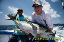 Zwei Angler auf den Malediven präsentieren stolz einen großen, glitzernden Fisch an Bord eines Bootes. Sonnige Meereskulisse unter blauem Himmel. Perfekter Ort für ein unvergessliches Angelabenteuer. Ideal für Meeresangeln-Enthusiasten.