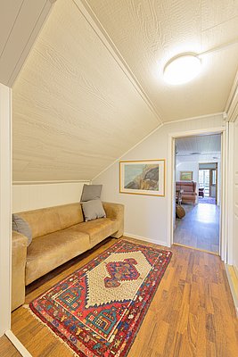 Gemütlicher nordischer Wohnbereich in Nordland, Norwegen. Helle Holzverkleidung, bequeme Ledercouch, bunte Teppiche. Perfekte Unterkunft für Angelurlaub in atemberaubender Umgebung, ideales Ambiente für Entspannung und Abenteuer.
