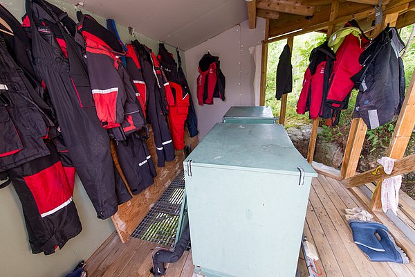 Angelkutten und Schwimmwesten hängen in einem Holzanbau auf Hitra, Norwegen. Perfekte Vorbereitung für einen erfolgreichen Angelurlaub in dieser atemberaubenden und fischreichen Region. Ideal für passionierte Meerangler.