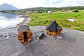 Hölzerne Sauna und Grillhütte in malerischer Küstenregion Nord-Norwegens, umgeben von Bergen und grünen Feldern. Perfekter Ort für Entspannung und Abenteuer.