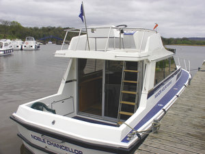 Hausboot am River Erne in Irland, festgemacht an einem Steg. Ideal für einen erholsamen Angelurlaub inmitten der Natur. Umgeben von ruhigem Wasser und grüner Landschaft. Perfekt für Outdoor-Abenteuer und Entspannung.