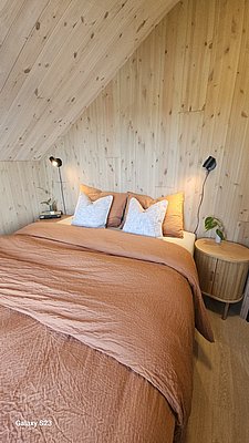 Gemütliches Schlafzimmer in Norwegen mit Holzvertäfelung und warmem Bettzeug. Ideal für entspannten Angelurlaub in Hitra und Umgebung. Perfekte Kombination aus Komfort und rustikalem Charme.