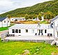 Weißes Haus in Nordland, Norwegen, umgeben von Hügeln und grüner Landschaft. Perfekte Unterkunft für entspannende Angelreisen. Entdecke die Ruhe und Schönheit der norwegischen Natur für ein unvergessliches Angelerlebnis.