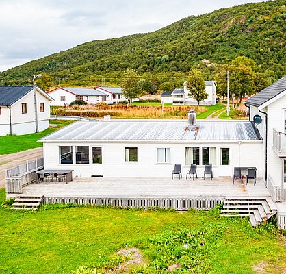 Weißes Haus in Nordland, Norwegen, umgeben von Hügeln und grüner Landschaft. Perfekte Unterkunft für entspannende Angelreisen. Entdecke die Ruhe und Schönheit der norwegischen Natur für ein unvergessliches Angelerlebnis.