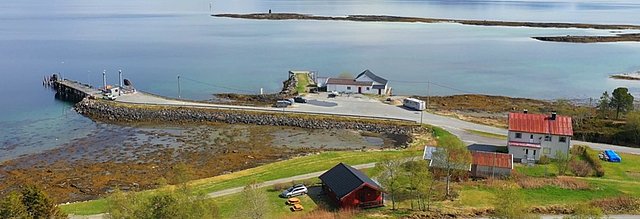 Küstenlandschaft in Nordland, Norwegen: Malerische Häuser und ein Kai am klaren Wasser. Perfekter Ort für Angelurlaub mit beeindruckender Naturkulisse. Ideal für Erholung und fischreiche Abenteuer in atemberaubender Umgebung.