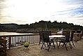 Holzveranda mit Sitzmöglichkeiten bietet Blick auf die norwegische Küste in Nordland. Sonnenuntergang über Bäumen und Wasser. Ideal für Angelurlaub und Entspannung. Perfekte Ausgangslage für Meeresangeln und Naturerlebnisse.