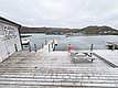 Küstenblick in Nord-Norwegen: Holzdeck mit Bank am Skarsvåg Turistsenter, Bootssteg und ruhiges Meer. Perfekt für Angelreisen und Erholung in spektakulärer Naturkulisse. Ideal für entspannte Momente am Wasser.