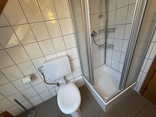 Helles, gefliestes Badezimmer in Hitra, Norwegen. Ausstattung: Toilette, Duschkabine, Wandregale. Ideal für komfortable Unterbringung bei Angelreisen in der Region. Pflegeleicht und sauber.