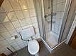 Helles, gefliestes Badezimmer in Hitra, Norwegen. Ausstattung: Toilette, Duschkabine, Wandregale. Ideal für komfortable Unterbringung bei Angelreisen in der Region. Pflegeleicht und sauber.