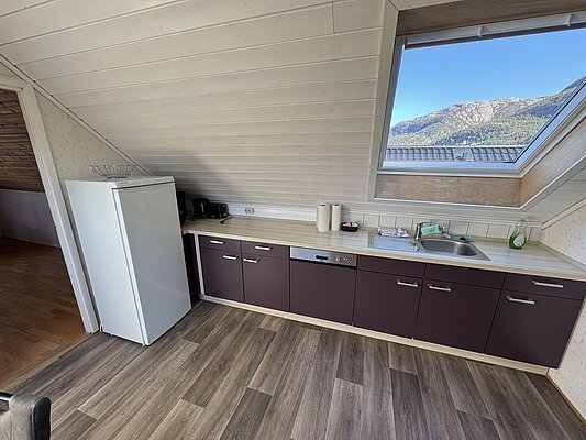 Gemütliche Küche in Hitra, Norwegen, mit modernen Geräten und großem Dachfenster. Traumhafter Bergblick. Ideal für Angelurlauber, die nach Abenteuer und Komfort suchen. Perfekter Ausgangspunkt für Erkundungen der Region und Meeresangeln.