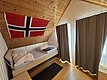 Gemütliches Gästezimmer in Hitra, Norwegen: Holzwände, norwegische Flagge, bequeme Betten, viel Tageslicht. Ideal für Angelliebhaber und Abenteuer in der malerischen Umgebung. Perfekte Unterkunft für entspannte Angelreisen.