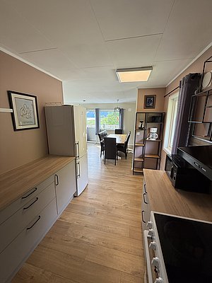 Gemütliche Ferienunterkunft in Nord-Norwegen: Moderne Küche, Esstisch, helle Räume, Holzboden, Blick ins Grüne. Perfekt für Angelurlaub und Entspannung. Entdecke Skandinaviens Schönheit in stilvollem Komfort. Optimaler Ausgangspunkt für Meeresabenteuer.