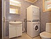 Badezimmer in Norwegen mit Waschmaschine und Trockner, Waschbecken mit Spiegel, Toilette und grauen Wänden. Ideal für komfortable Angelurlaube in Nordland.
