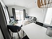 Gemütliches Wohnzimmer in Nord-Norwegen mit moderner Einrichtung. Große Fenster bieten Ausblick auf den Hafen. Ideal für Angelurlauber, die Komfort und skandinavische Landschaft genießen möchten. Perfekter Rückzugsort nach einem erfolgreichen Angeltag.
