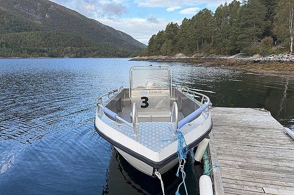 Ein Aluminium-Angelboot liegt am Holzsteg in Hitra, Norwegen. Umgeben von ruhigem Wasser und bewaldeten Hügeln, ideal für Angelabenteuer. Perfekter Ausgangspunkt für einen unvergesslichen Angelurlaub in Skandinavien.