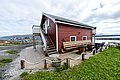 Rotes Ferienhaus in Nord-Norwegen direkt am Wasser mit Terrasse und Sitzbereich. Perfekt für einen erholsamen Angelurlaub mit malerischem Blick auf Berge und das Meer. Ideal für Natur- und Angelbegeisterte.