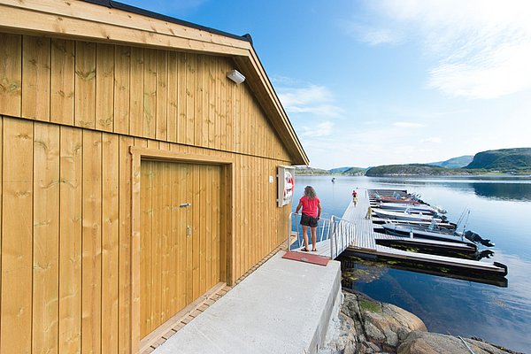 Holzhaus an malerischem Steg in der Region Hitra, Norwegen. Friedliche Landschaft mit Booten und klarer See, ideal für Angelreisen. Perfekter Ausgangspunkt für unvergessliche Angelausflüge.