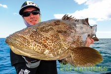 Ein Angler hält stolz einen großen, gefleckten Fisch vor der Küste Süd-Norwegens. Klare blaue Himmel und Meer im Hintergrund. Perfekte Bedingungen für Angelreisen und Meeresangeln. Abenteuerlust und Fangchancen garantiert.