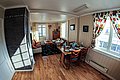 Gemütliches Wohnzimmer einer skandinavischen Ferienwohnung in Nord-Norwegen. Helle Holzböden, bunte Vorhänge, ein Esstisch und ein Sofa schaffen eine einladende Atmosphäre. Perfekt für Angelurlaub in malerischer Umgebung.