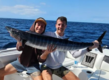 Erfolgreicher Angelausflug in São Vicente, Kapverden: Zwei Angler präsentieren stolz ihren gefangenen Wahoo auf einem Boot vor der tiefblauen Kulisse des Atlantiks. Perfektes Angelziel für Abenteurer.