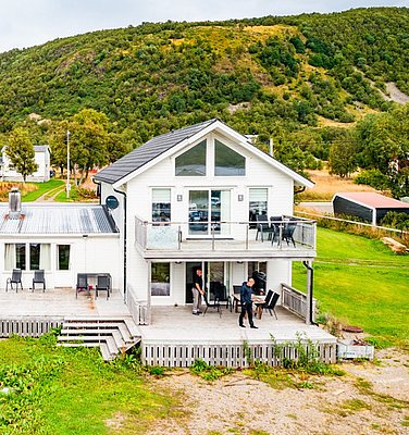 Modernes Ferienhaus in Nordland, Norwegen, umgeben von grünen Hügeln und landschaftlicher Ruhe. Perfekte Unterkunft für einen Angelurlaub, mit großzügiger Terrasse und malerischem Ausblick. Entspannung und Natur pur erleben.