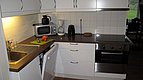 Moderne, gut ausgestattete Küchenzeile in Hitra, Norwegen, mit weißen Schränken, Edelstahlgeräten und gemütlicher Beleuchtung für komfortables Kochen während deines Angelurlaubs. Ideal, um frischen Fang selbst zuzubereiten.