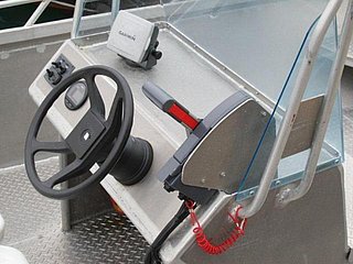 Schiffskonsole in Südwest-Norwegen: Lenkrad, Steuerhebel und technisches Gerät auf metallischem Boden. Ideal für Angelreisen und Bootsabenteuer in der Region.