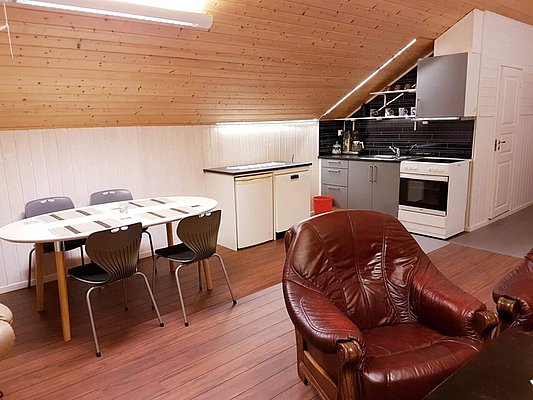 Gemütliche Ferienwohnung in Nord-Norwegen mit Holzdecke, moderner Küche, Esstisch für sechs Personen und Ledersesseln. Ideal für Angelurlauber, die Komfort und Erholung nach einem aufregenden Tag auf dem Meer suchen.