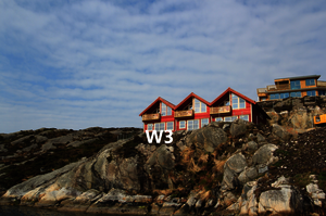 Rote Holzhäuser thronen auf felsiger Küste in Südwest-Norwegen. Die dramatische Landschaft lädt zum Entdecken ein, ideal für Angelreisen. Blauer Himmel und klare Luft versprechen Erholung und Abenteuer in einzigartiger Umgebung.