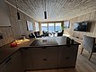 Gemütliches Ferienhaus auf Hitra, Norwegen. Holzverkleidung, moderne Küche, geräumiger Wohnbereich mit Blick aufs Meer. Perfekt für Angelurlaub und Entspannung am Fjord. Große Fensterflut lassen viel Licht herein. Ideal für Abenteuer und Erholung.