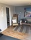 Gemütliches Wohnzimmer in Nordland, Norwegen: Skandinavisches Design mit Holzmöbeln, grauen Wänden, einem Sessel und einem Sofa. Angenehme Atmosphäre lädt zum Entspannen nach einem erlebnisreichen Angeltag ein. Ideal für Angelreisen und Erholung.