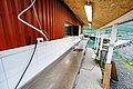 Außenbereich eines Fischverarbeitungsstandes in Nord-Norwegen, mit Edelstahl-Arbeitsfläche und Spüle, neben einem malerischen Hafen mit Booten – idealer Startpunkt für Angelreisen.