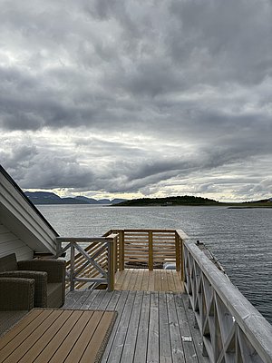 Hölzerner Steg am ruhigen Fjord in Nord-Norwegen, unter bewölktem Himmel. Perfekt für Angelreisen und Naturerlebnisse mit atemberaubendem Blick auf die Küstenlandschaft.