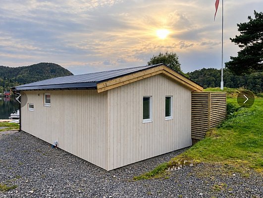 Gemütliches Ferienhaus in Hitra, Norwegen: Holzhütte am Wasser, umgeben von grüner Natur und Fjorden. Perfekt für Angelreisen und Naturliebhaber. Skandinavisches Ambiente bei Sonnenuntergang. Ideal für entspannten Angelurlaub in faszinierender Umgebung.